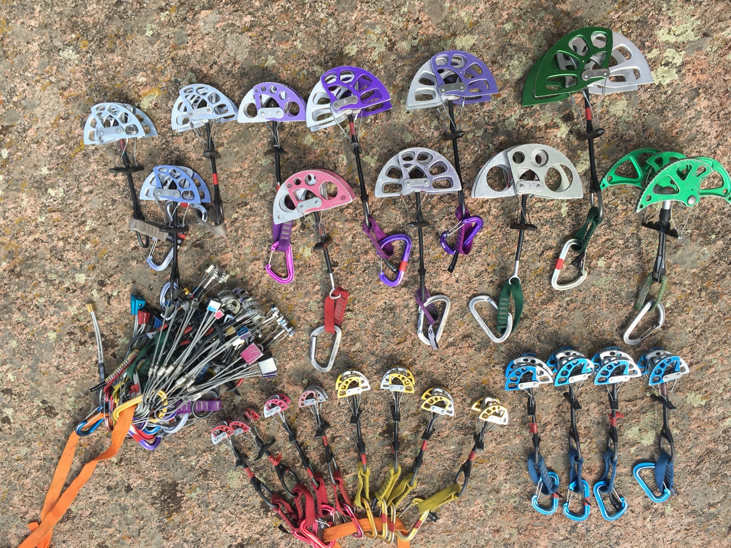 A full rack of camming devices laid out on granite