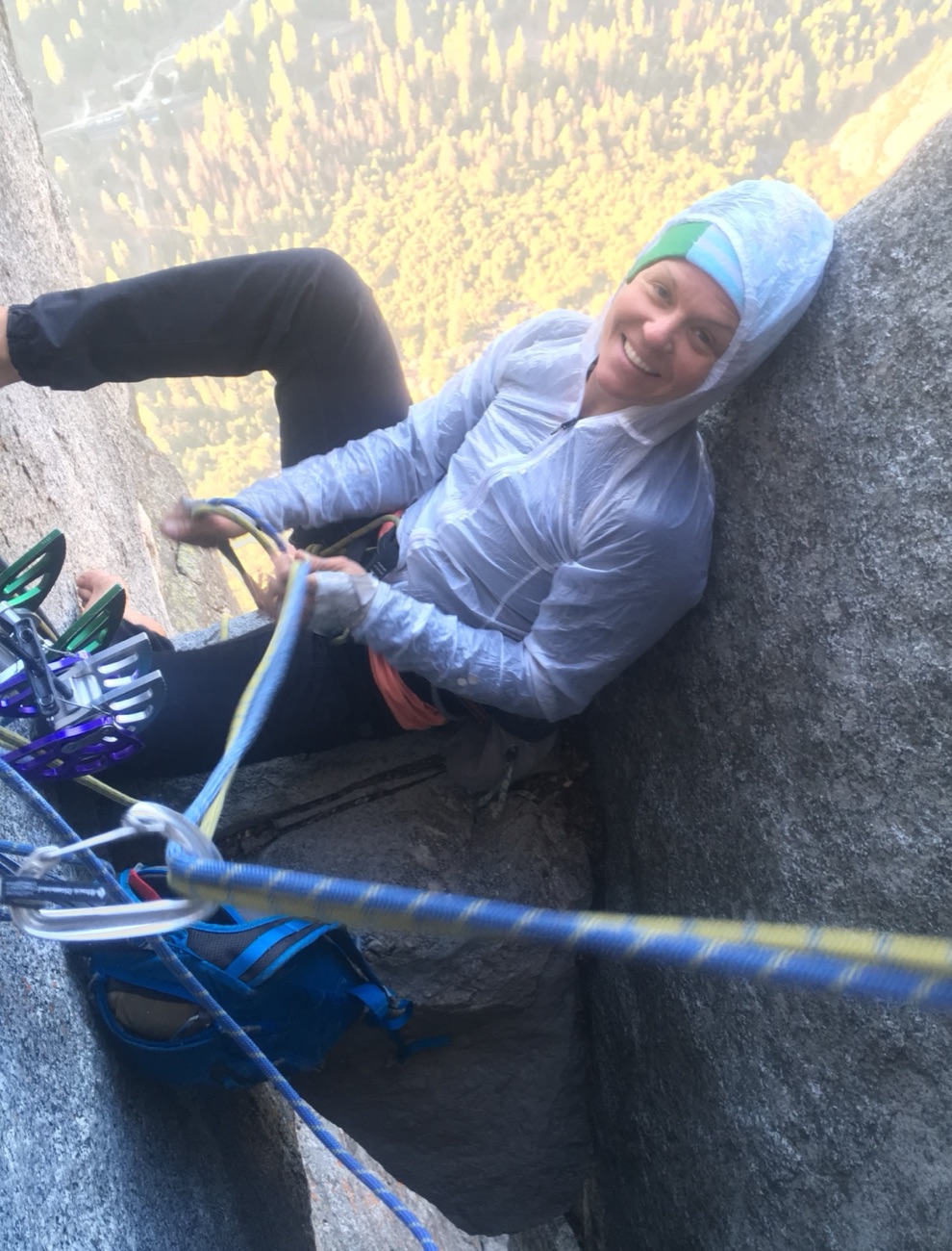 Marta on a big-wall belay high above the valley, in a white wind jacket