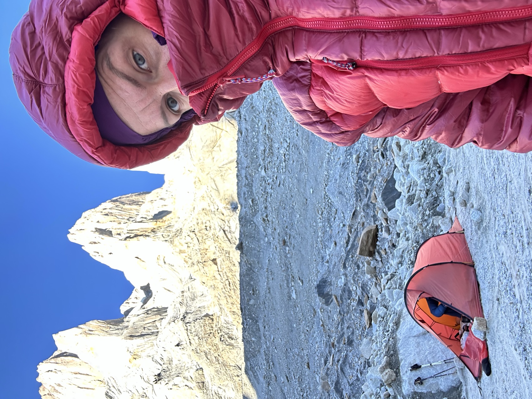 Marta below a granite spire on a glacier, an orange tent at her camp