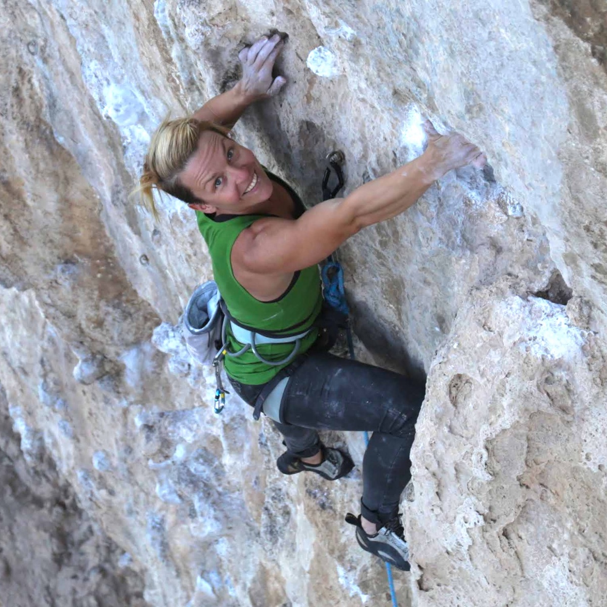 Marta climbing steep limestone, smiling at the camera