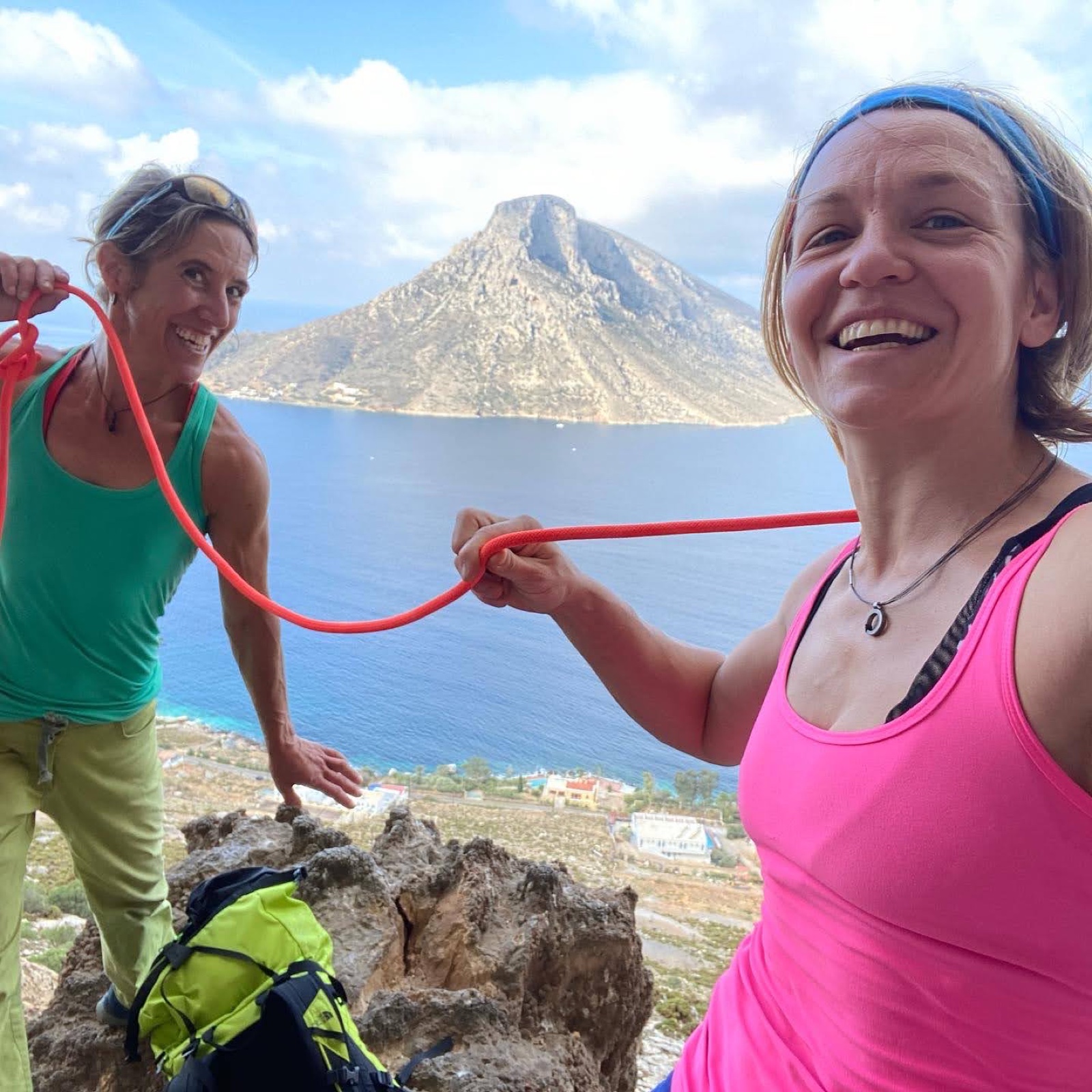 Two women laughing over a shared rope above the sea