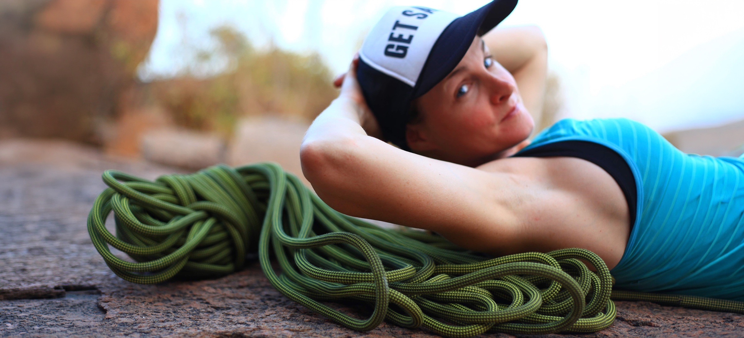 A climber resting on the rock beside a coiled rope
